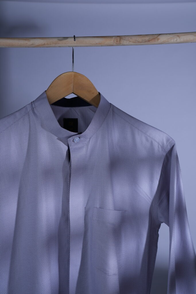 A grey shirt hanging on a rod for the ultimate guide to Finding the Perfect Men's Tailored Shirt